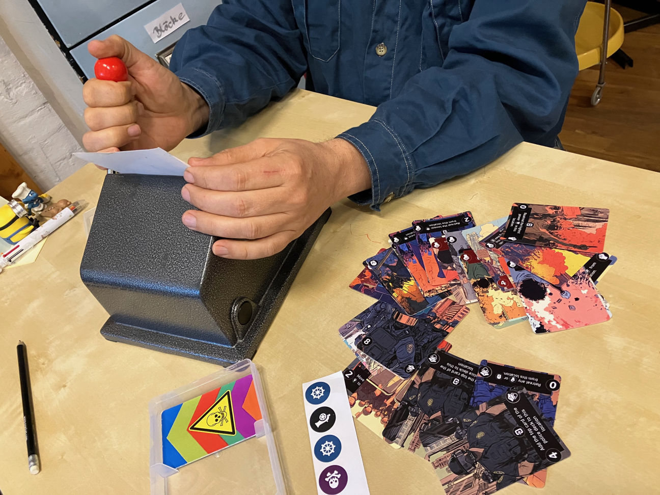 Neue Spielkarten werden gestanzt, auf dem Tisch liegen bereits gestanzte Karten